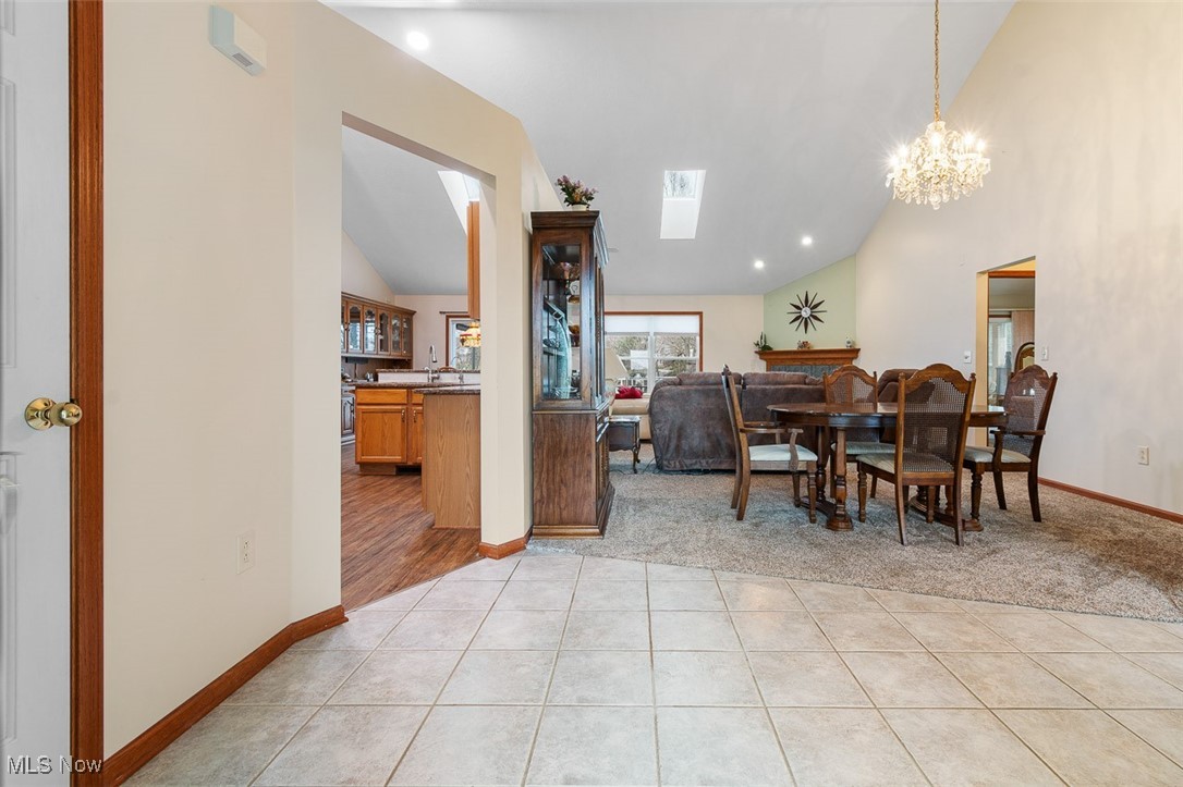 2271 Graybill Road Uniontown, OH 44685 - Photo 14 of 44 Entry and dining room featuring high vaulted ceiling, light tile patterned floors, a chandelier, a skylight, and baseboards