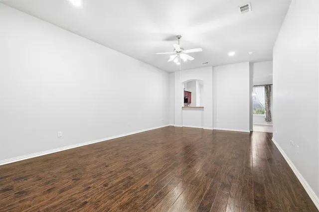an empty room with wooden floor and ceiling fan