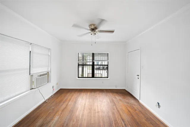 an empty room with wooden floor chandelier and windows