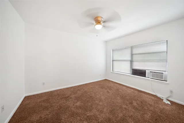 an empty room with windows and chandelier fan