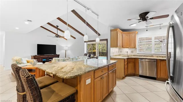 a kitchen with stainless steel appliances kitchen island granite countertop a sink and a refrigerator