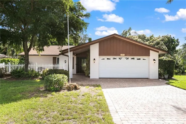 a view of a white house with a yard and large tree