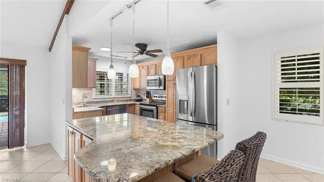 a kitchen with stainless steel appliances granite countertop a table chairs and a refrigerator