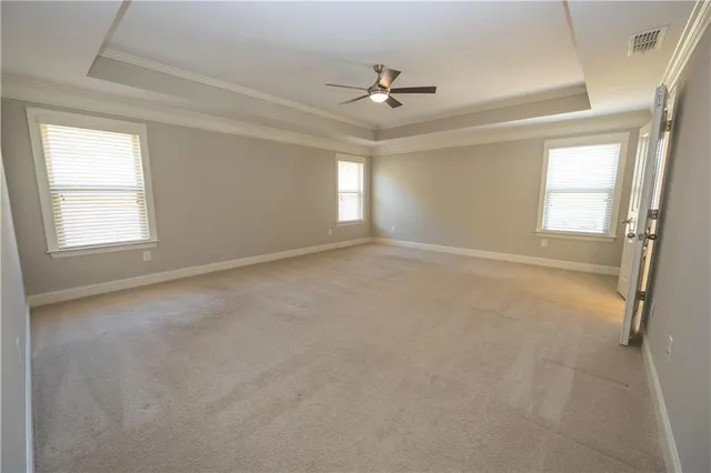 an empty room with windows and ceiling fan