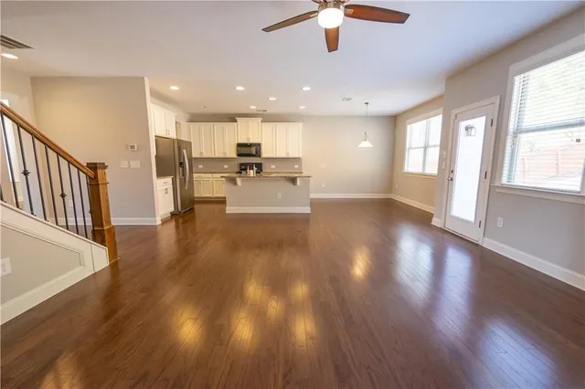 a view of a kitchen with a stove cabinets a ceiling fan and wooden floor