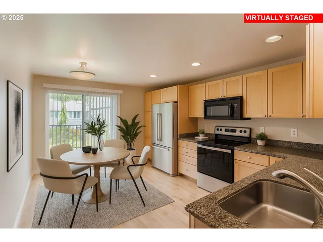 a kitchen with stainless steel appliances granite countertop a refrigerator a sink dishwasher a stove and a dining table with wooden cabinet