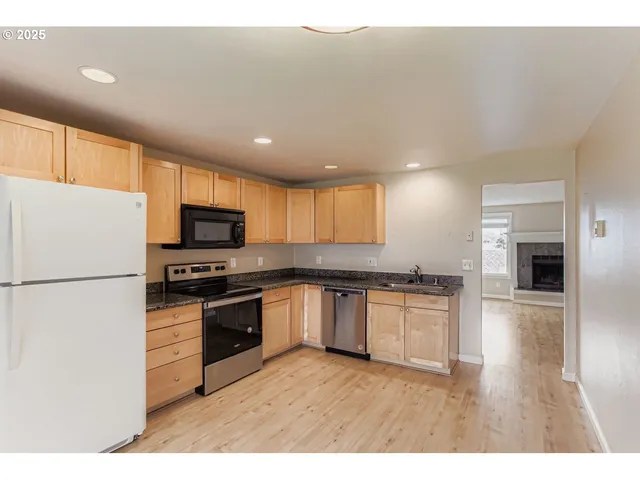 a kitchen with granite countertop a refrigerator stove top oven and sink