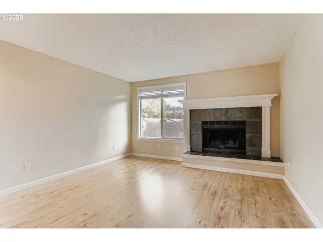 a view of an empty room with a fireplace and a window