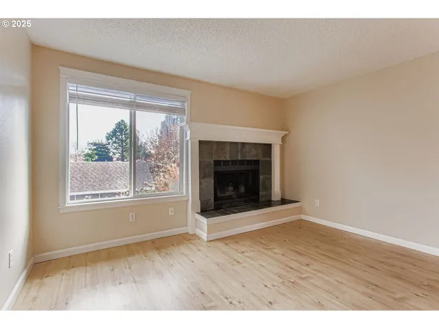 an empty room with wooden floor and fireplace
