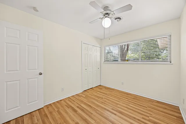 a view of empty room with wooden floor and fan
