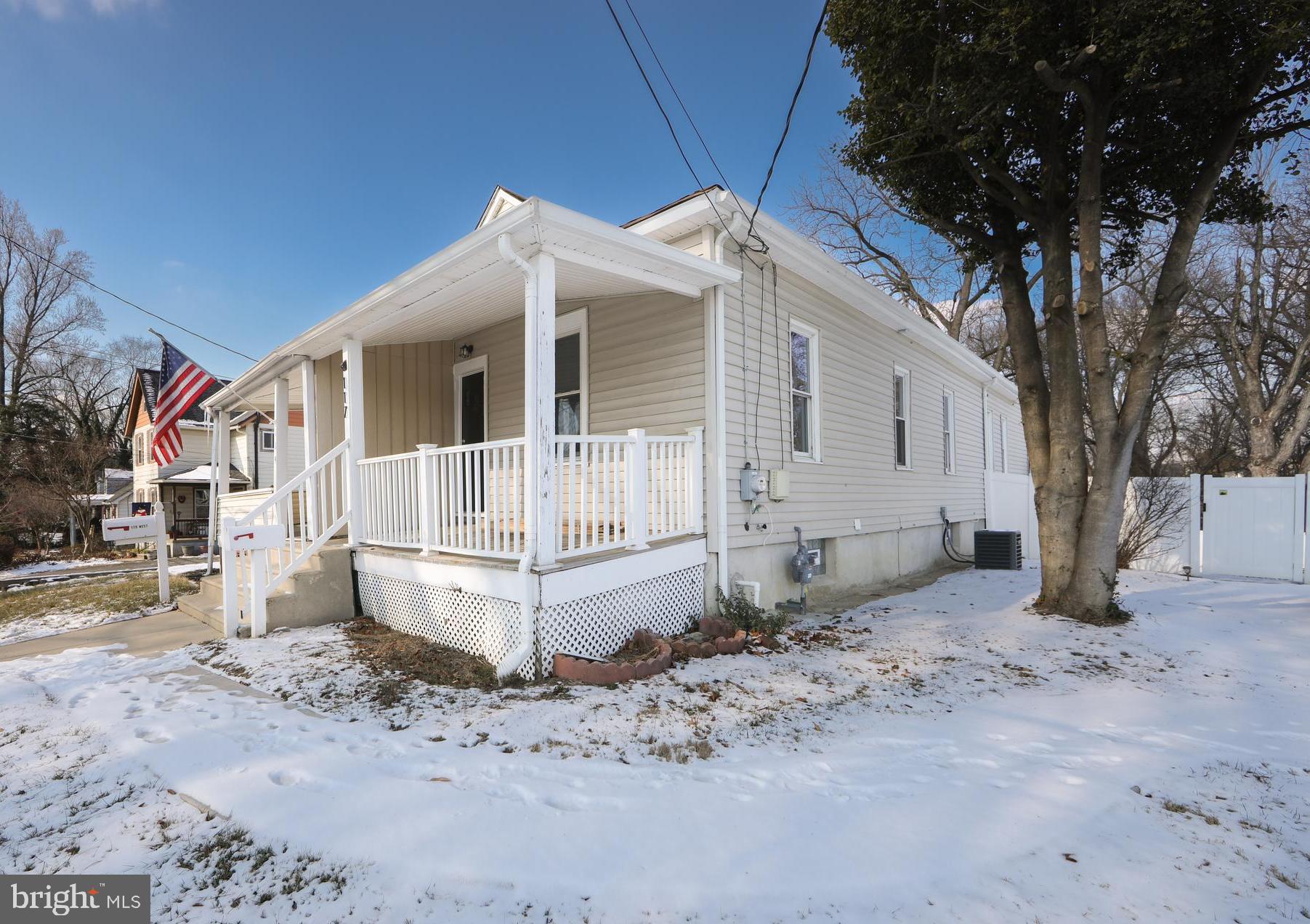 a view of a white house with a large tree in front of it