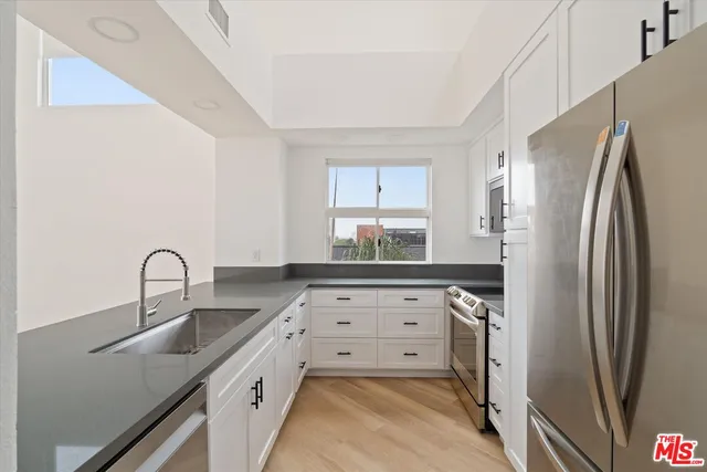 a kitchen with stainless steel appliances granite countertop a refrigerator and a sink