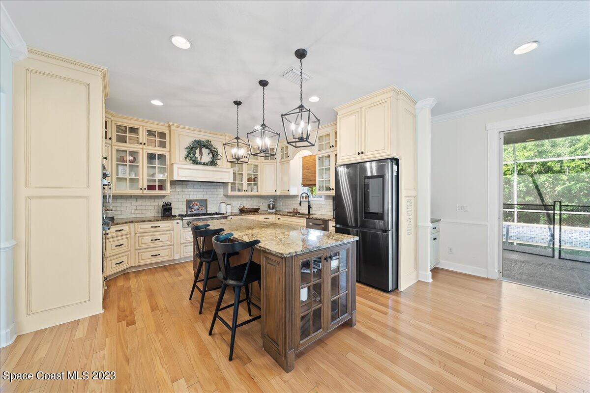 250 Baytree Drive Melbourne, FL 32940 - Photo 14 of 61 a kitchen with stainless steel appliances kitchen island granite countertop a refrigerator a stove a sink dishwasher and a dining table with wooden floor