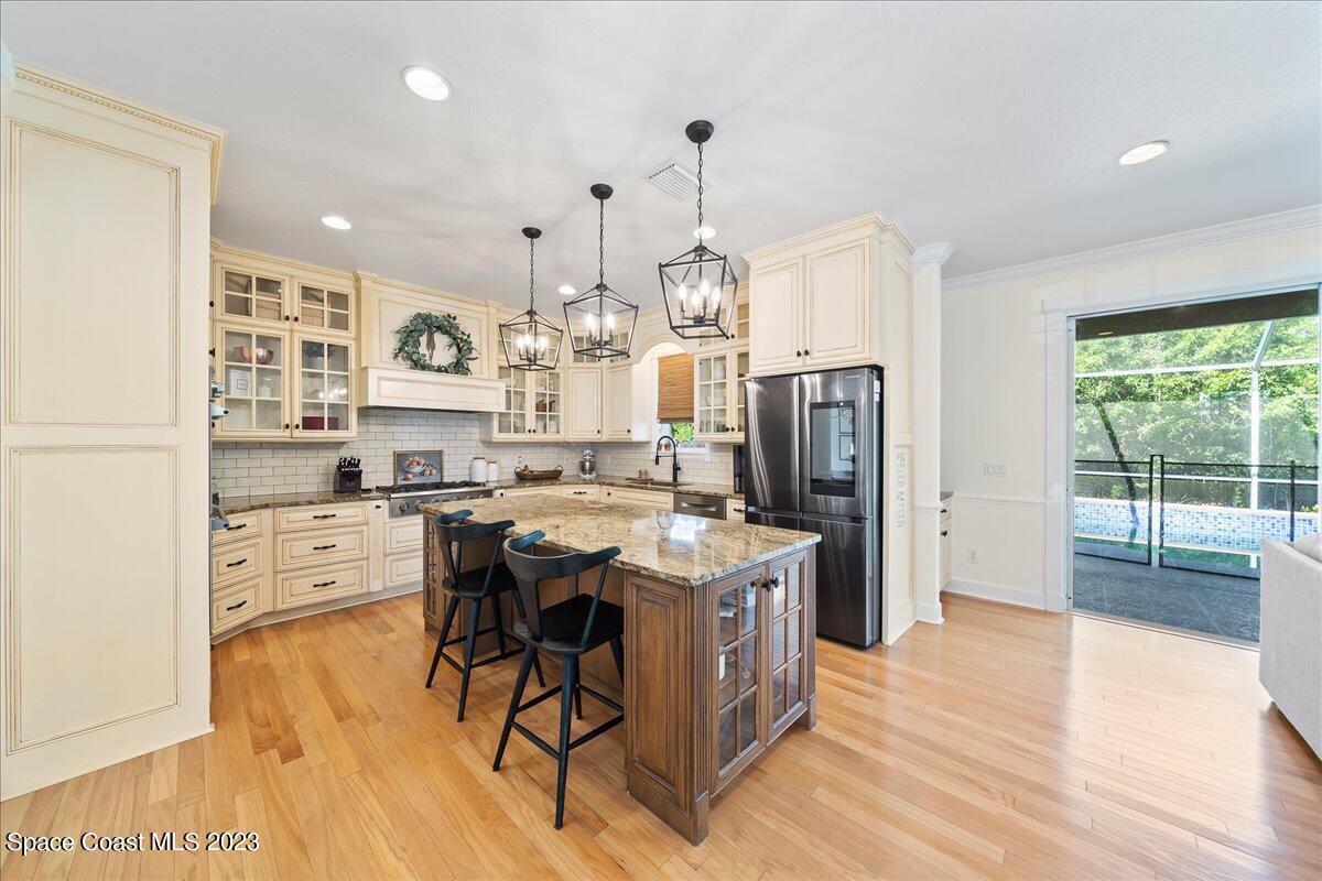 250 Baytree Drive Melbourne, FL 32940 - Photo 17 of 61 a kitchen with stainless steel appliances kitchen island granite countertop a refrigerator a stove a sink dishwasher and white cabinets with wooden floor