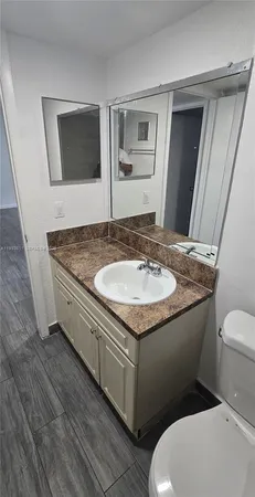 a bathroom with a granite countertop toilet sink and mirror