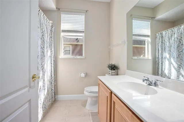 a bathroom with a granite countertop sink a toilet a shower and a mirror