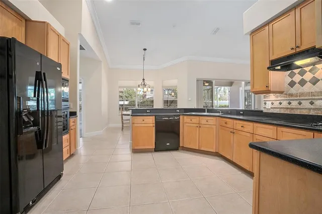a large kitchen with stainless steel appliances kitchen island granite countertop a refrigerator and a sink
