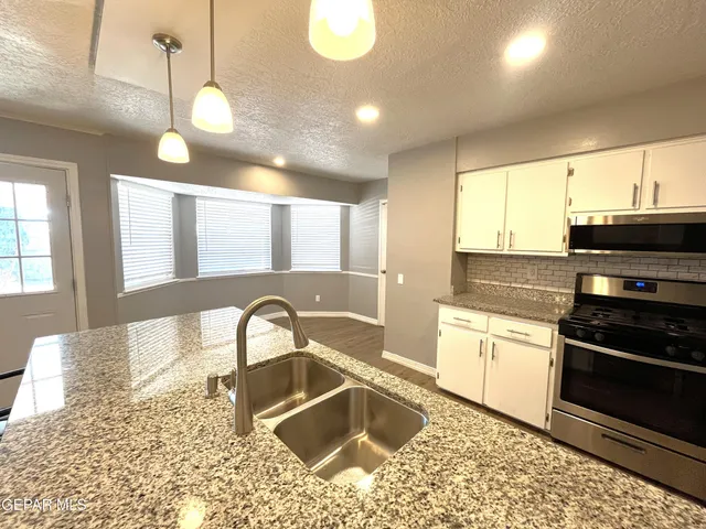 a kitchen with stainless steel appliances granite countertop a sink a stove top oven a granite counter space and cabinets