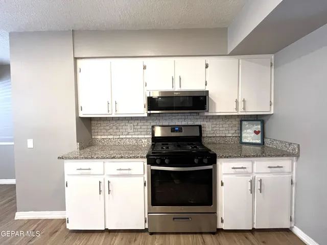 a kitchen with stainless steel appliances granite countertop a sink a stove and a wooden floors