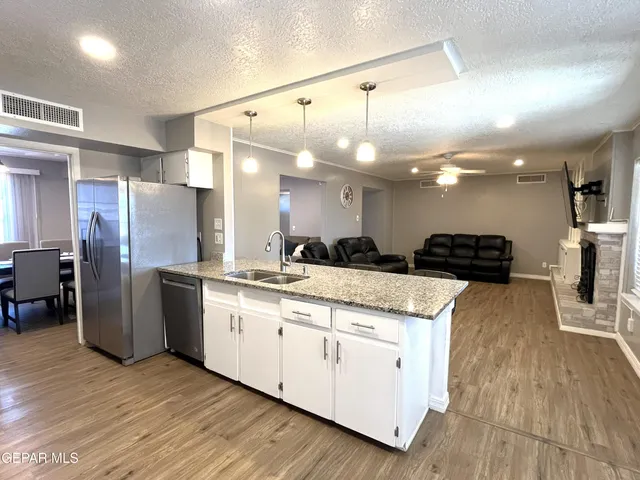 a large kitchen with stainless steel appliances kitchen island granite countertop a large counter top and stove top oven with wooden floor