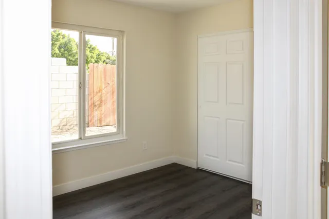 an empty room with wooden floor and windows