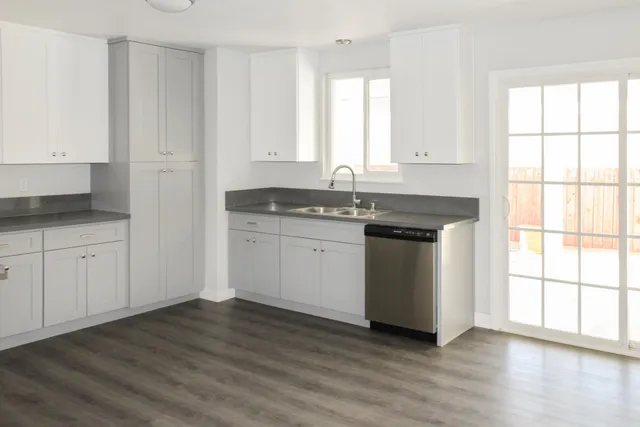a kitchen with granite countertop white cabinets sink and window