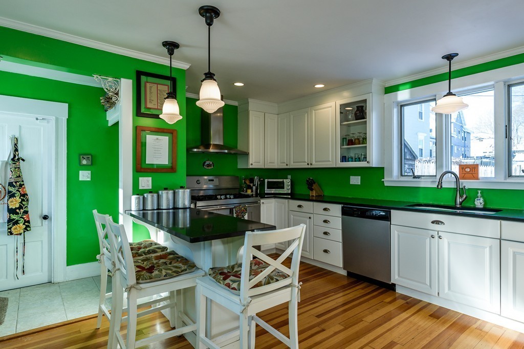 68 Maple Street Boston, MA 02132 - Photo 8 of 19 a kitchen with stainless steel appliances granite countertop a stove a sink dishwasher a dining table and chairs with wooden floor