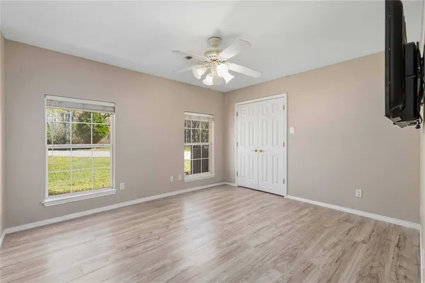 an empty room with wooden floor fan and windows