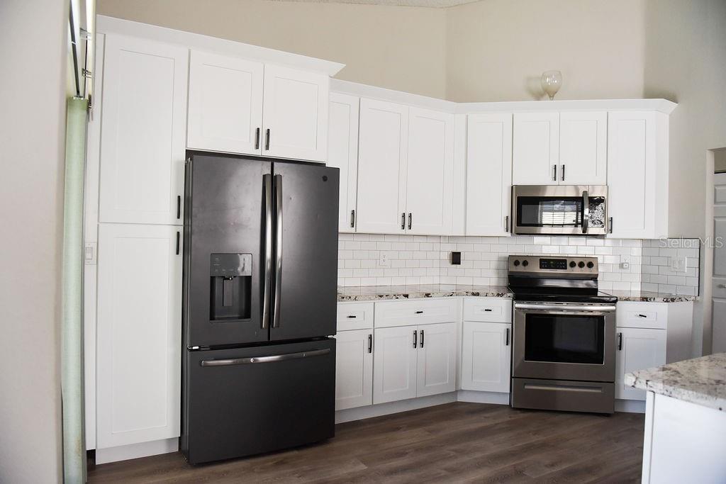 4819 West Raintree Bradenton, FL 34203 - Photo 7 of 37 a kitchen with stainless steel appliances white cabinets and a refrigerator