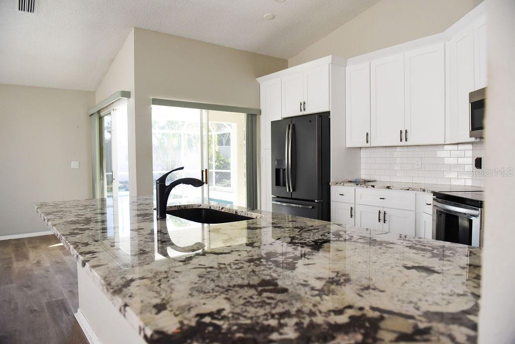 4819 West Raintree Bradenton, FL 34203 - Photo 9 of 37 a kitchen with stainless steel appliances kitchen island granite countertop a stove a sink and a refrigerator