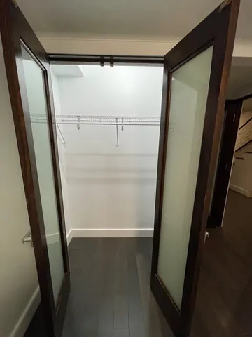 an empty room with wooden floor and fan