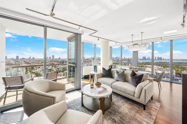 a living room with furniture large windows and wooden floor