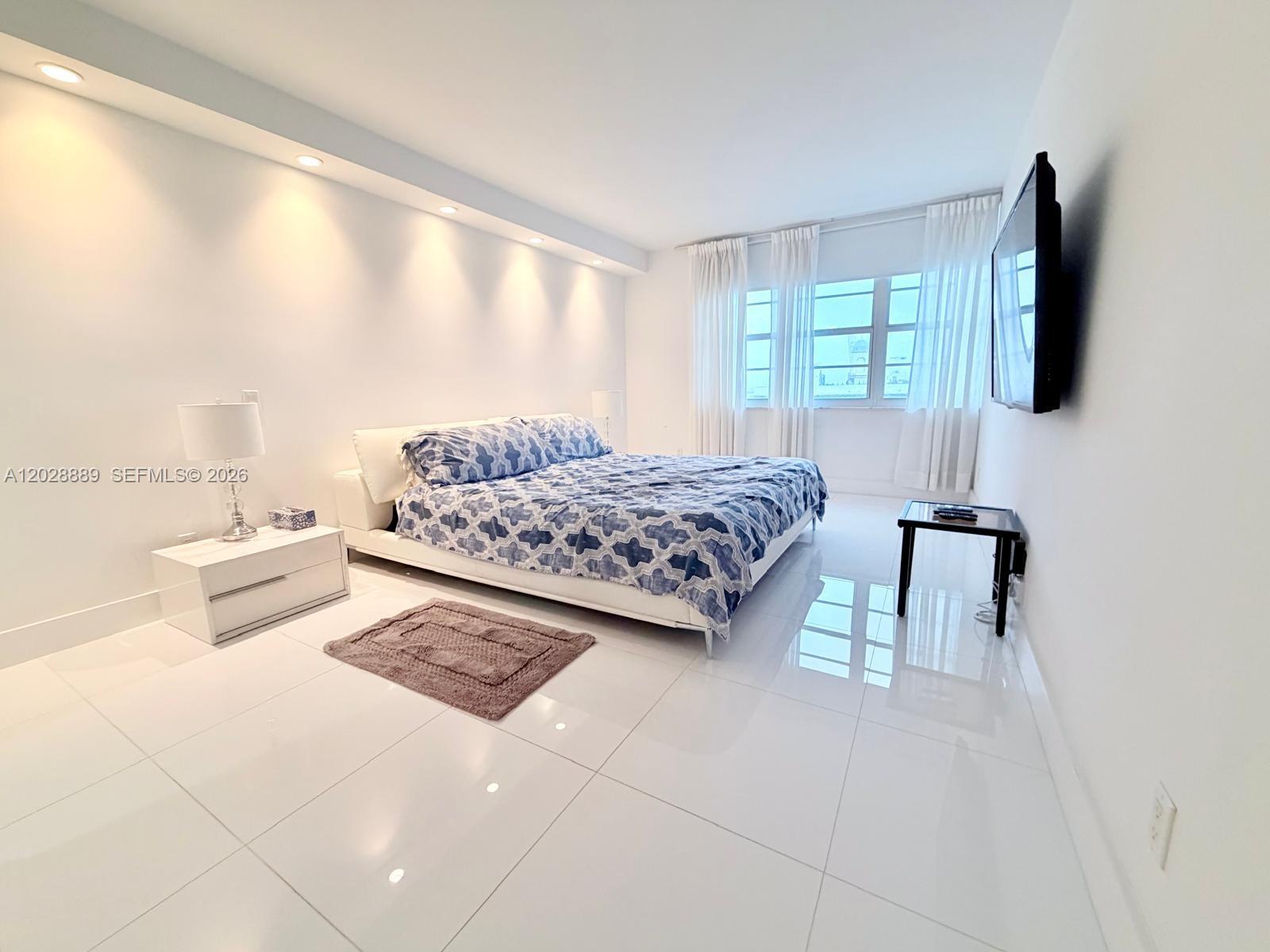 100 Lincoln Road, Unit 1504 Miami Beach, FL 33139 - Photo 8 of 17 a bedroom with a bed a flat screen tv and a large window