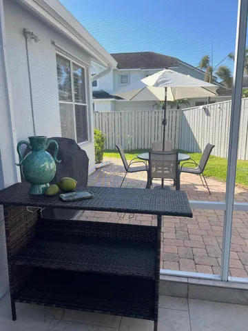 a view of a deck with table and chairs under an umbrella with a small yard