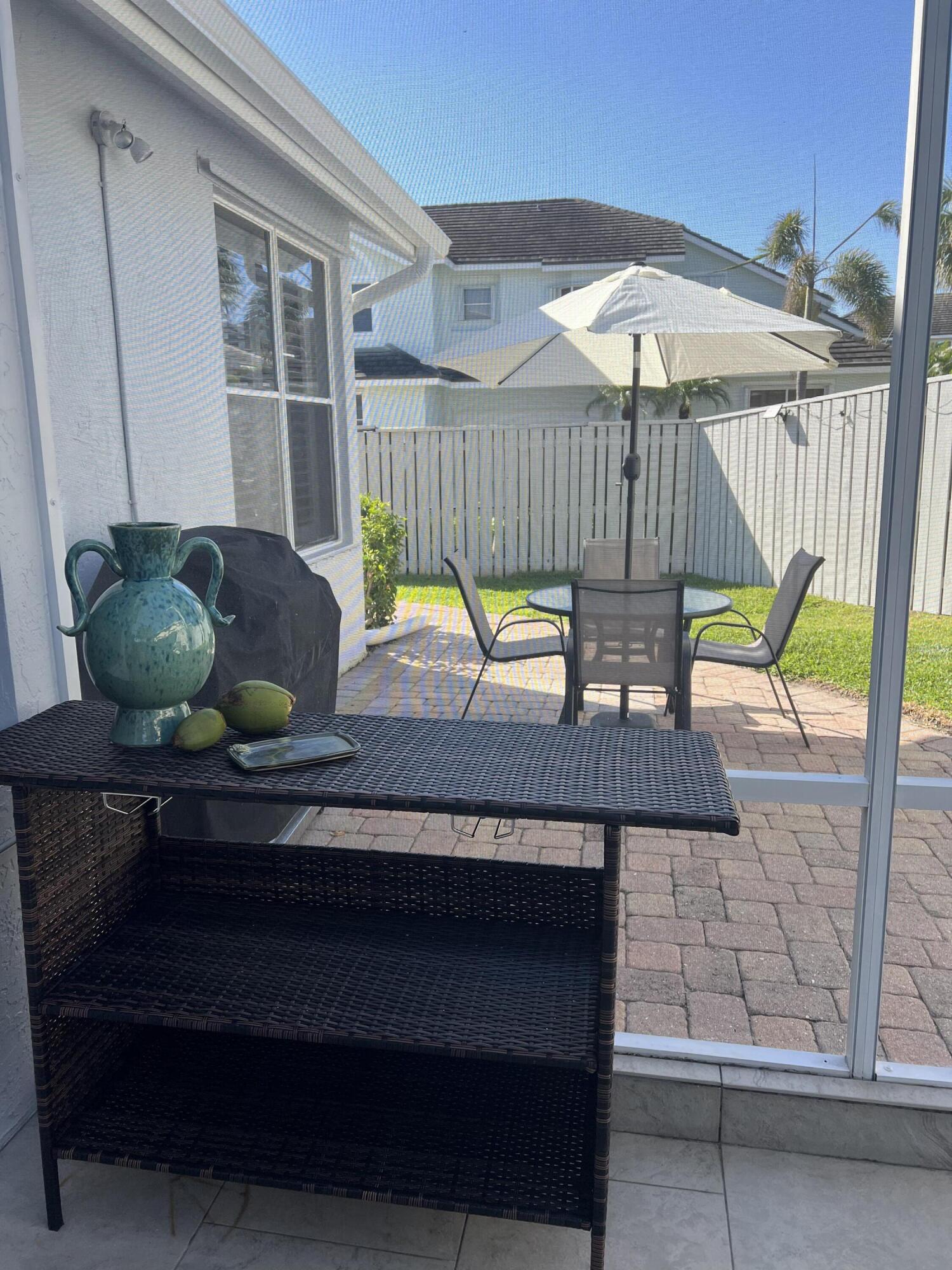 3028 Windward Way Jupiter, FL 33477 - Photo 31 of 48 a view of a deck with table and chairs under an umbrella with a small yard