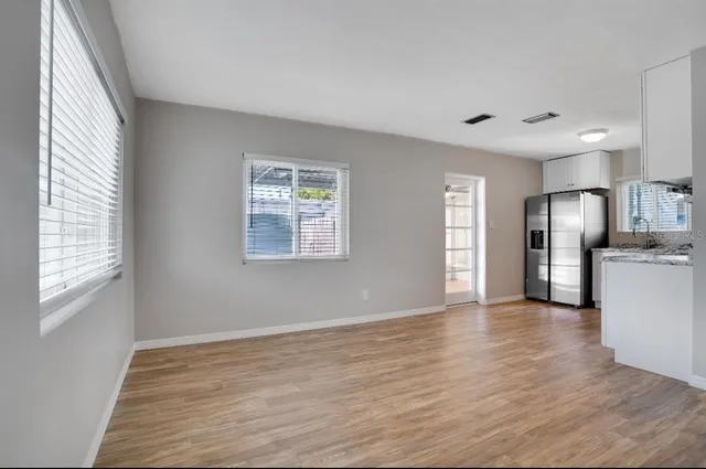a view of an empty room with window and wooden floor
