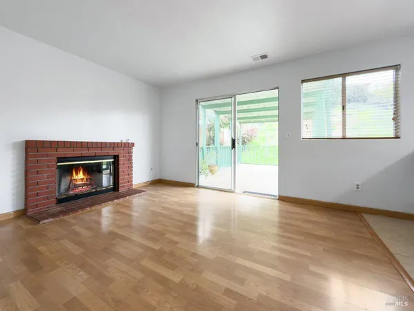 an empty room with floor to ceiling windows and fireplace