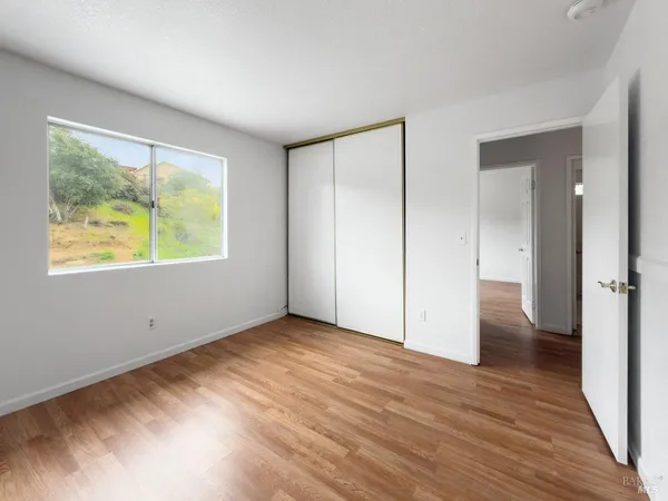 a view of an empty room with wooden floor and a window
