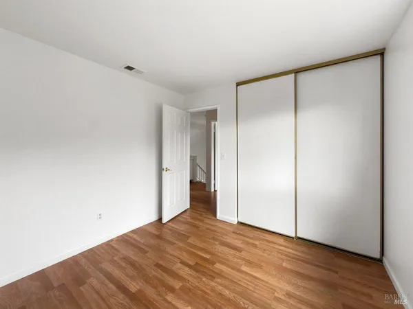 a view of an empty room with wooden floor and closet