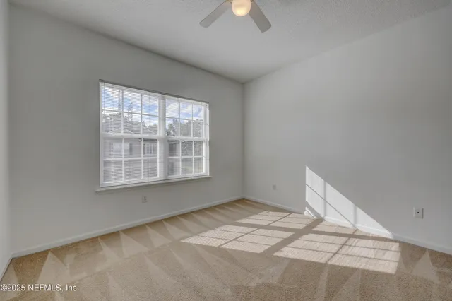 a view of a big room with windows and chandelier fan