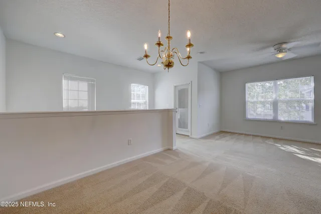 an empty room with windows and chandelier fan