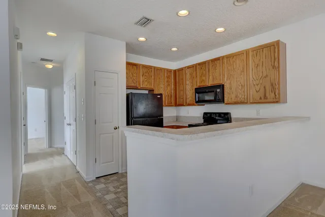a view of kitchen with stainless steel appliances cabinets and a refrigerator