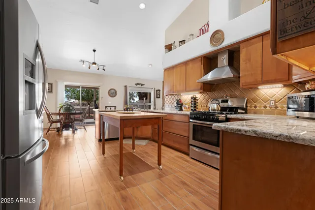 a kitchen with stainless steel appliances granite countertop wooden floors stove top oven and cabinets
