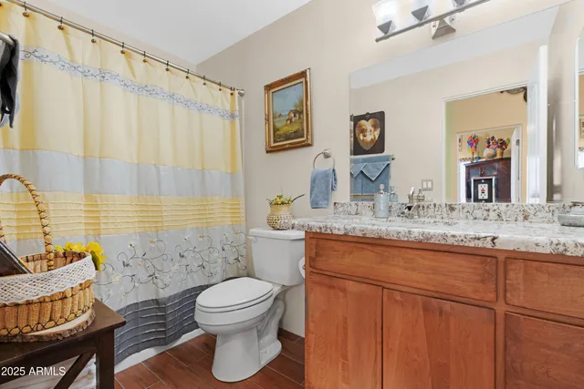 a bathroom with a granite countertop sink toilet a mirror and shower curtain