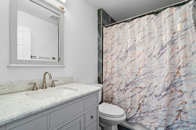 a bathroom with a granite countertop sink and a toilet