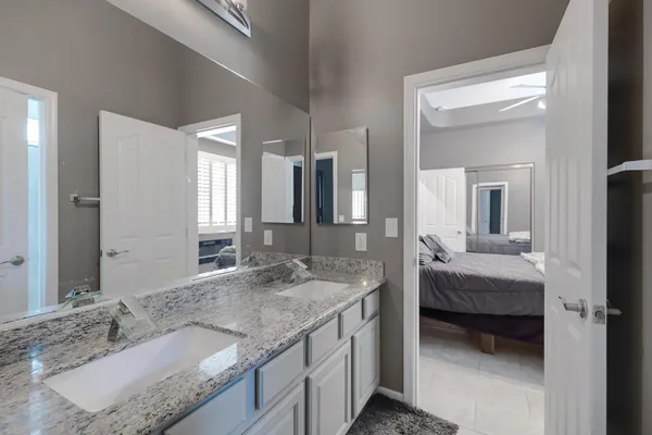 a en suite bathroom with sinks granite countertop and a mirror