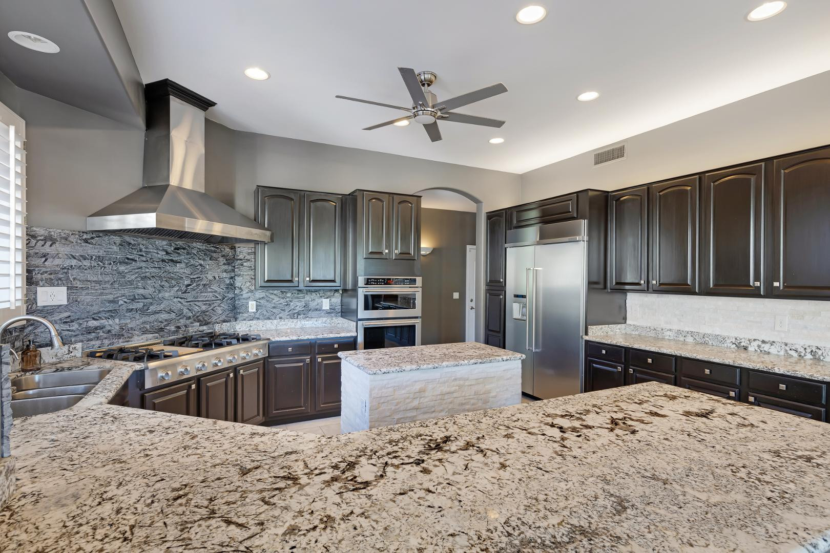 8540 East McDowell Road, Unit 10 Mesa, AZ 85207 - Photo 2 of 25 a kitchen with stainless steel appliances kitchen island granite countertop a sink and a refrigerator