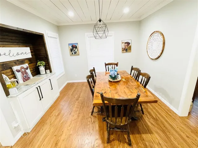 a dining room with wooden floor a chandelier a wooden table and chairs