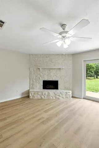 wooden floor with a ceiling fan and a fireplace