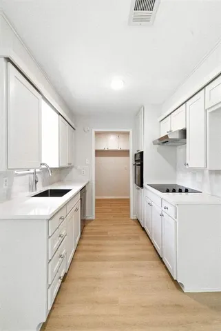 a large kitchen with stainless steel appliances a sink stove and cabinets